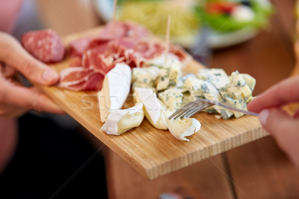 hands with blue cheese and jamon or ham on board Stock photo © dolgachov