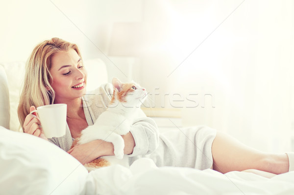 happy woman with coffee and cat in bed at home Stock photo © dolgachov