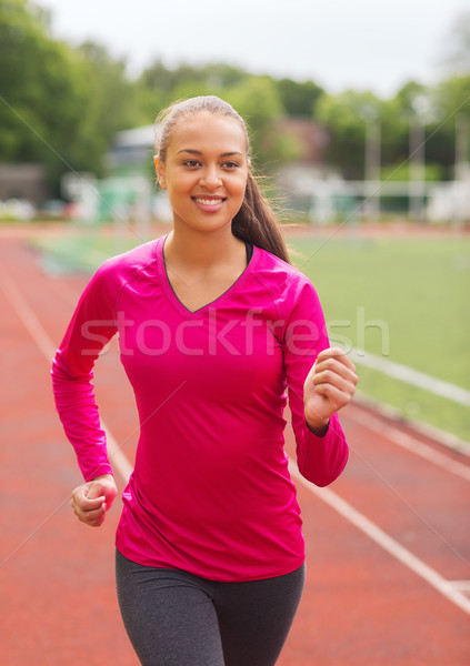 smiling young woman running on track outdoors Stock photo © dolgachov