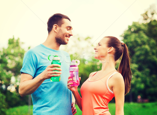 smiling couple with bottles of water outdoors Stock photo © dolgachov