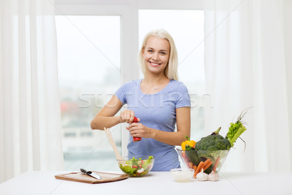 smiling woman cooking vegetable salad at home Stock photo © dolgachov