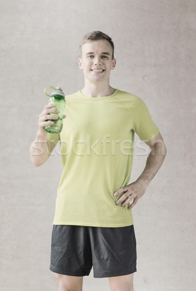 smiling man with bottle of water in gym Stock photo © dolgachov