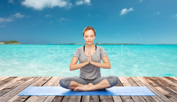 woman making yoga meditation in lotus pose on mat Stock photo © dolgachov