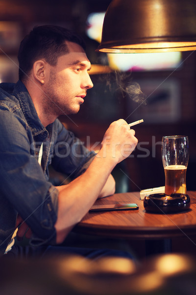 Homem potável cerveja fumador cigarro bar Foto stock © dolgachov