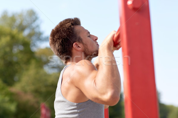 young man exercising on horizontal bar outdoors Stock photo © dolgachov