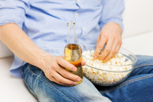 Stock photo: close up of man with popcorn and beer at home