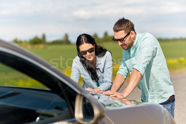 happy man and woman with road map on car hood Stock photo © dolgachov