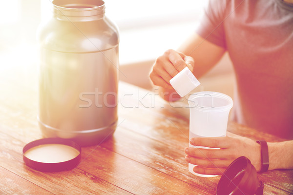 close up of man with protein shake bottle and jar Stock photo © dolgachov