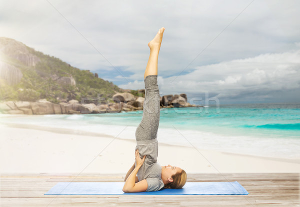 woman making yoga in shoulderstand pose on beach Stock photo © dolgachov