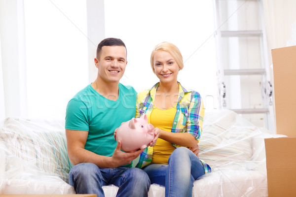 smiling couple with piggybank in new home Stock photo © dolgachov