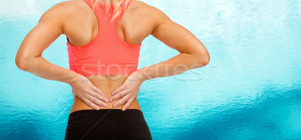 Stock photo: close up of sporty woman touching her back