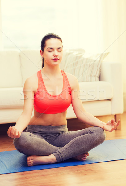 smiling teenager meditating at home Stock photo © dolgachov