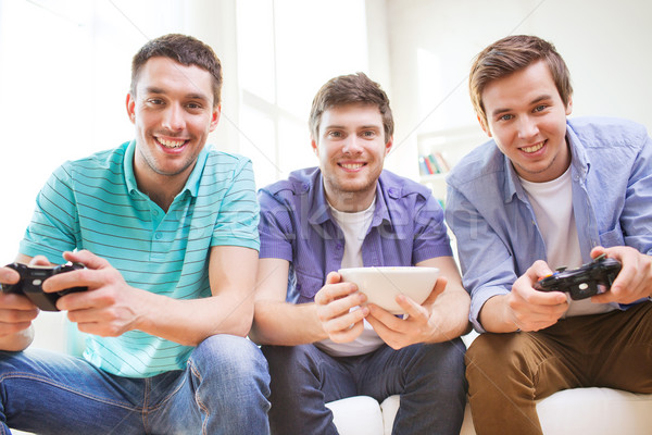 smiling friends playing video games at home Stock photo © dolgachov