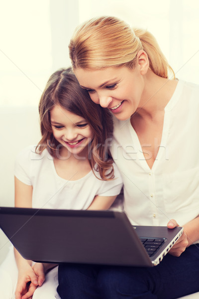 smiling mother and little girl with laptop at home Stock photo © dolgachov