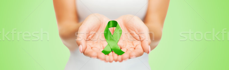 Stock photo: close up of hands holding green awareness ribbon