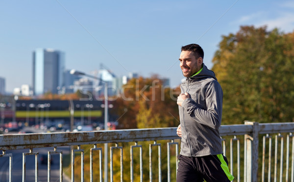happy young man running over city bridge Stock photo © dolgachov