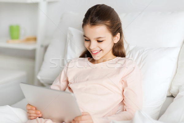 happy girl lying in bed with tablet pc at home Stock photo © dolgachov