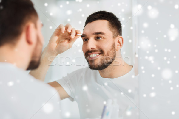 man with tweezers tweezing eyebrow at bathroom Stock photo © dolgachov