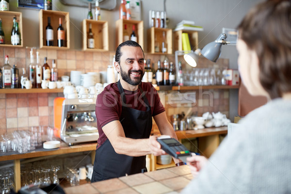 man or waiter with card reader and customer at bar Stock photo © dolgachov
