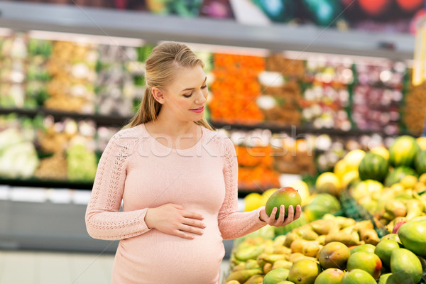 happy pregnant woman with mango at grocery store Stock photo © dolgachov