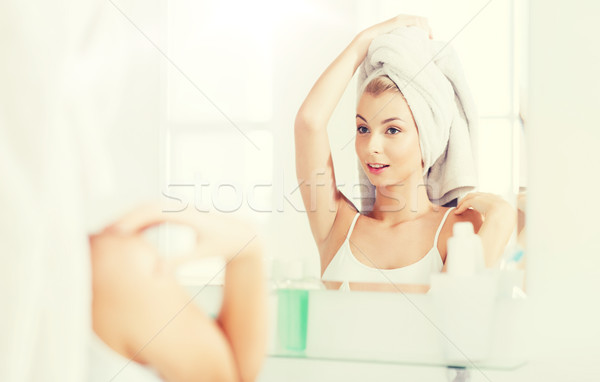 happy young woman with towel at mirror in bathroom Stock photo © dolgachov