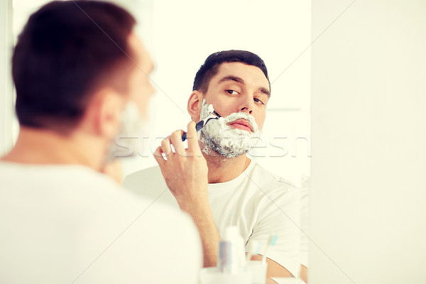 man shaving beard with razor blade at bathroom Stock photo © dolgachov