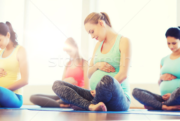 happy pregnant women exercising yoga in gym Stock photo © dolgachov