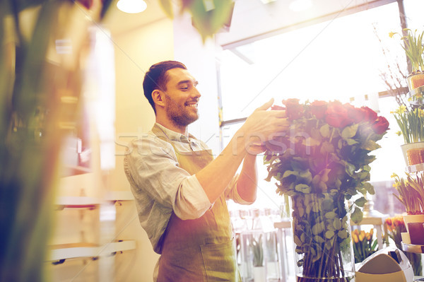 Stock photo: smiling florist man with roses at flower shop