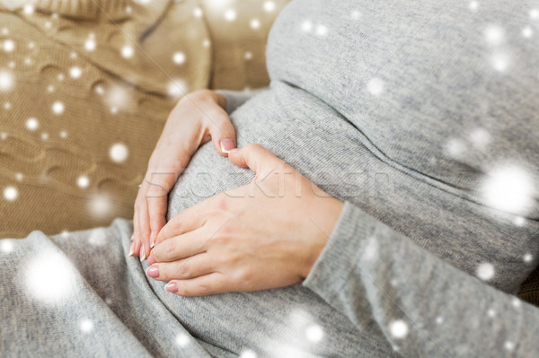 Stock photo: pregnant woman making heart gesture on her belly