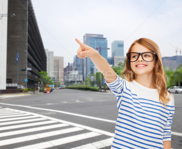 Stock photo: cute little girl in eyeglasses pointing in the air