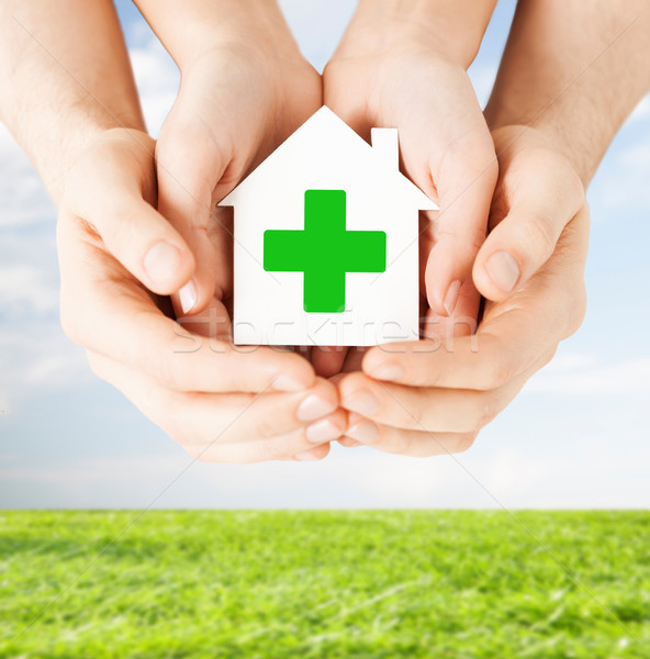Stock photo: hands holding paper house with green cross