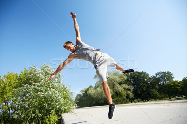 sporty young man jumping in summer park Stock photo © dolgachov