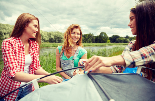 smiling friends setting up tent outdoors Stock photo © dolgachov