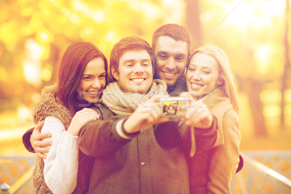 group of friends with photo camera in autumn park Stock photo © dolgachov