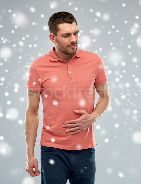 unhappy man suffering from stomach ache over snow Stock photo © dolgachov