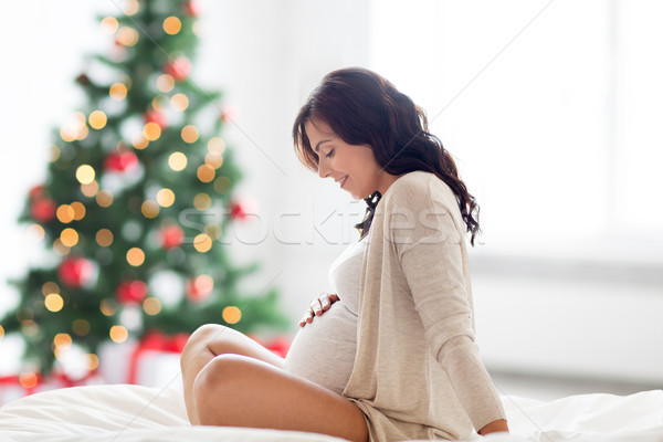 happy pregnant woman sitting on bed at christmas Stock photo © dolgachov