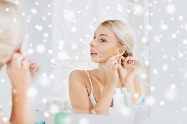 woman trying on earring looking at bathroom mirror Stock photo © dolgachov