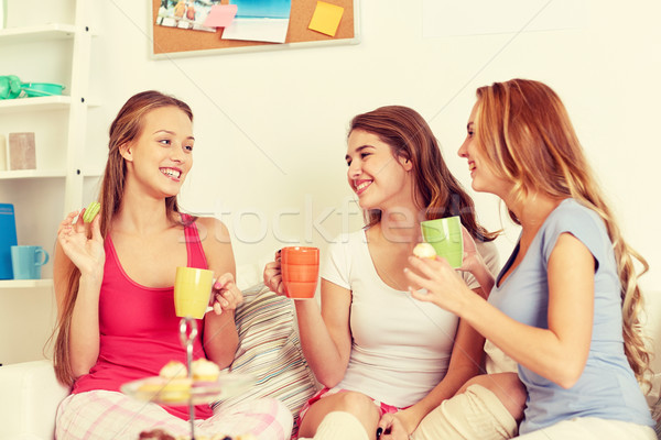 Fericit femeile tinere potabilă ceai dulciuri acasă Imagine de stoc © dolgachov