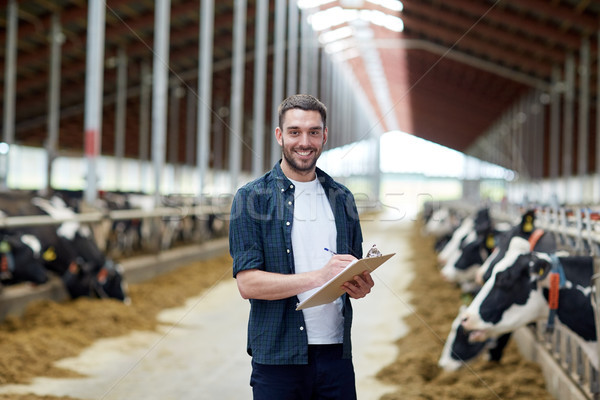 farmer with clipboard and cows in cowshed on farm Stock photo © dolgachov