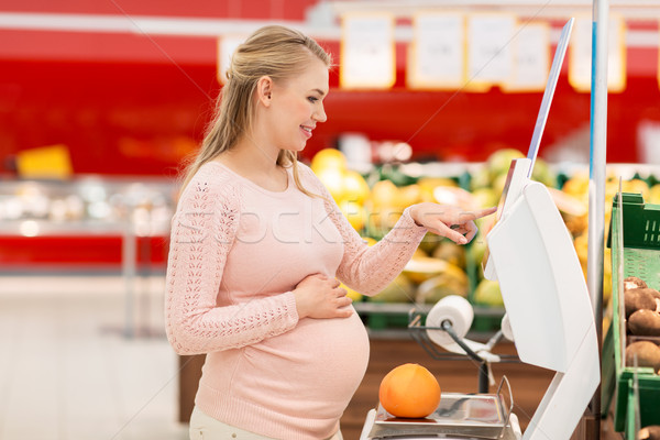 pregnant woman with grapefruit on scale at grocery Stock photo © dolgachov