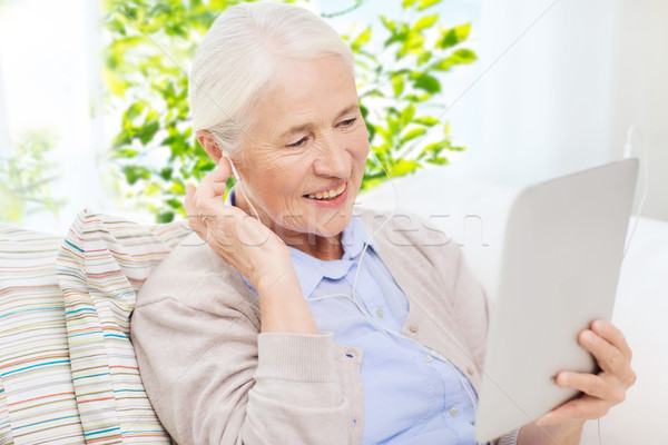 senior woman with tablet pc and earphones at home Stock photo © dolgachov