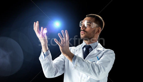 scientist in lab coat and goggles with light Stock photo © dolgachov