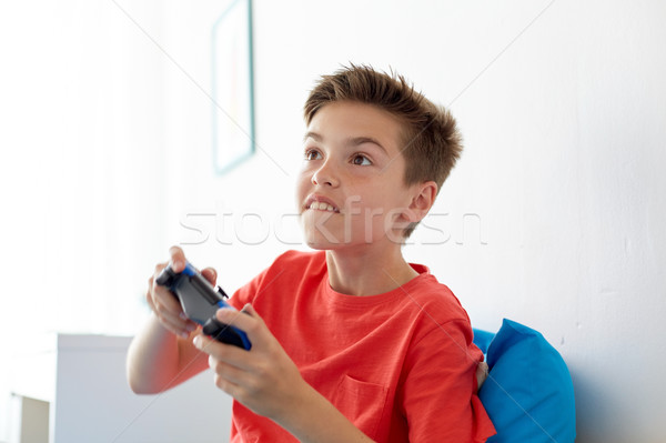 happy boy with gamepad playing video game at home Stock photo © dolgachov