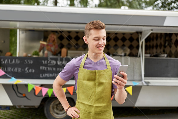 salesman in apron with smartphone at food truck Stock photo © dolgachov