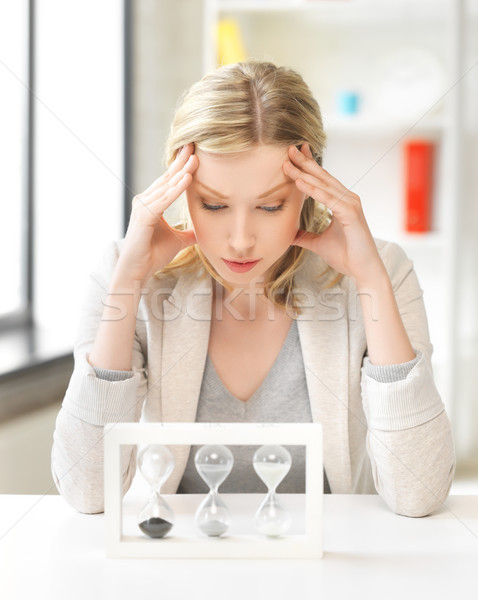 tired woman behind the table with hourgalss Stock photo © dolgachov