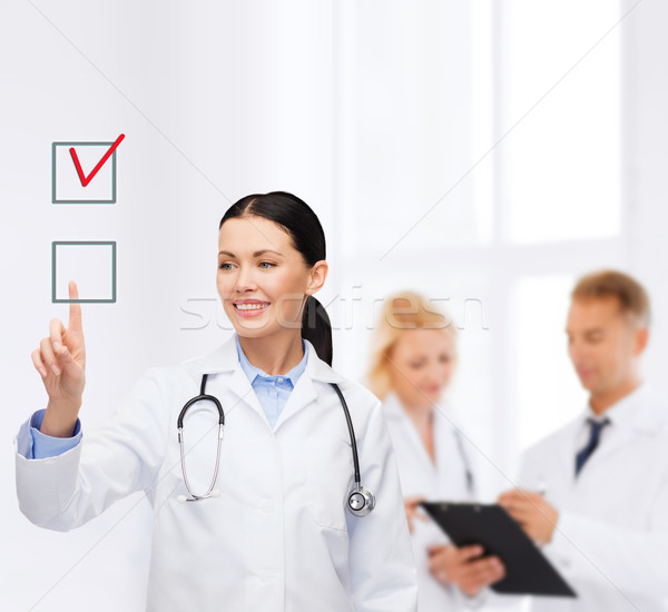 Uśmiechnięty kobiet lekarza wskazując checkbox opieki zdrowotnej Zdjęcia stock © dolgachov
