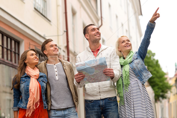 group of smiling friends with map exploring city Stock photo © dolgachov
