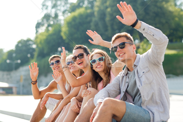 group of smiling friends sitting on city street Stock photo © dolgachov