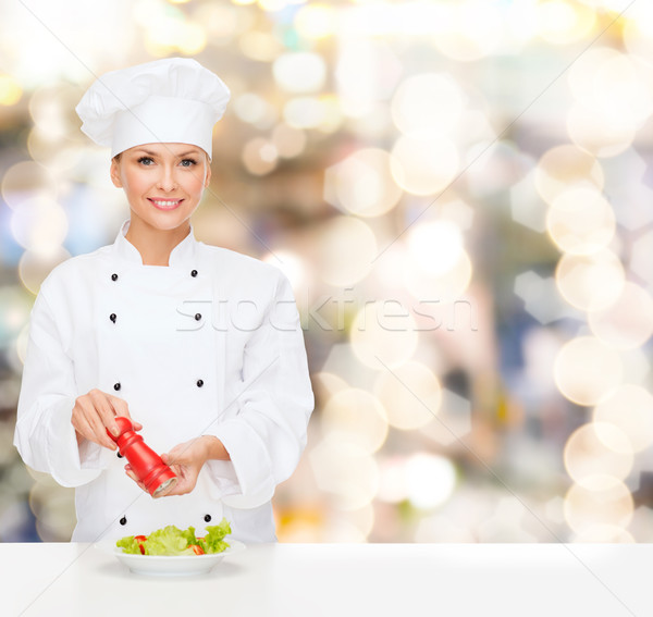 smiling female chef spicing vegetable salad Stock photo © dolgachov