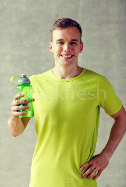 smiling man with bottle of water in gym Stock photo © dolgachov